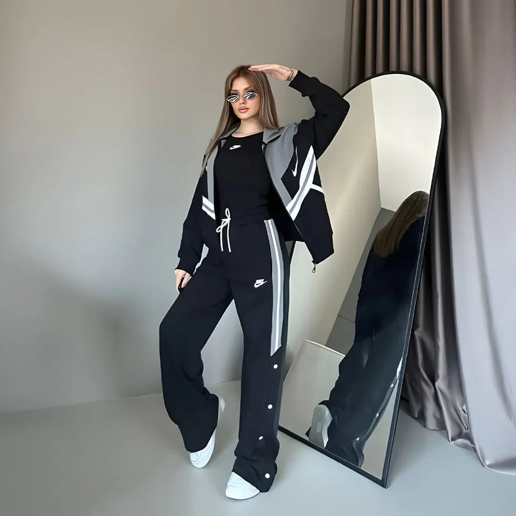 Person wearing a black tracksuit with white stripes in front of a mirror.