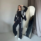 Person wearing a black tracksuit with white stripes in front of a mirror.