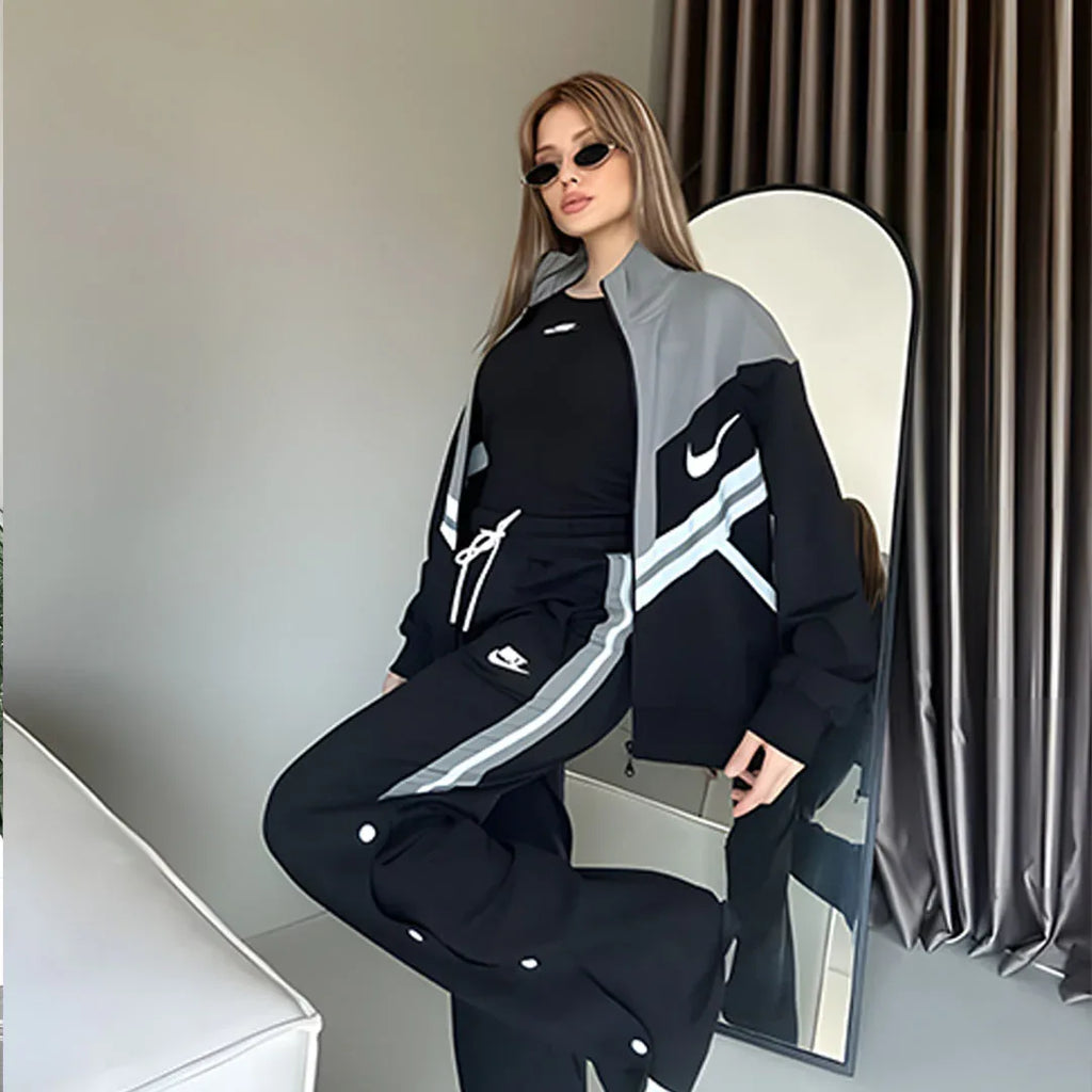 Person wearing a black and gray Nike tracksuit sitting on a chair.