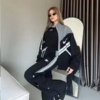 Person wearing a black and gray Nike tracksuit sitting on a chair.